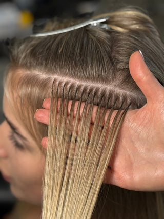 A woman gently brushing her long, healthy hair extensions.