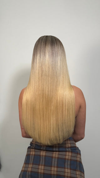 A joyful woman tossing her long, wavy hair in the sunlight.